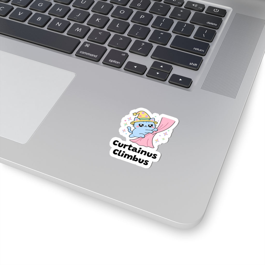 Curtainus Climbus wizard cat sticker stuck on a silver laptop next to the keyboard