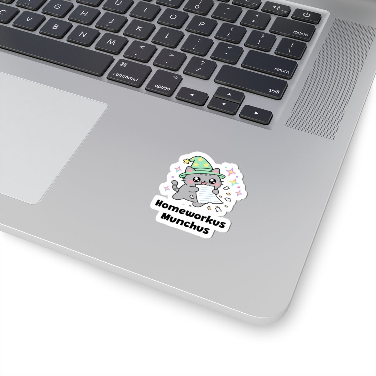 Homeworkus Munchus wizard cat sticker stuck on a silver laptop next to the keyboard