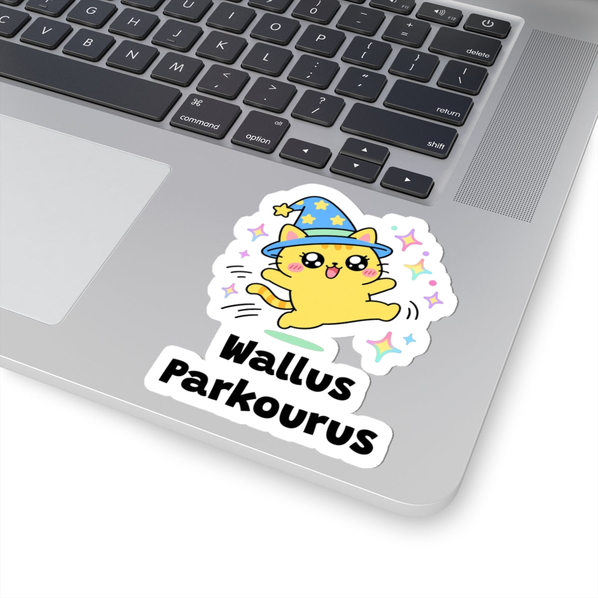 Wallus Parkourus wizard cat sticker stuck on a silver laptop next to the keyboard