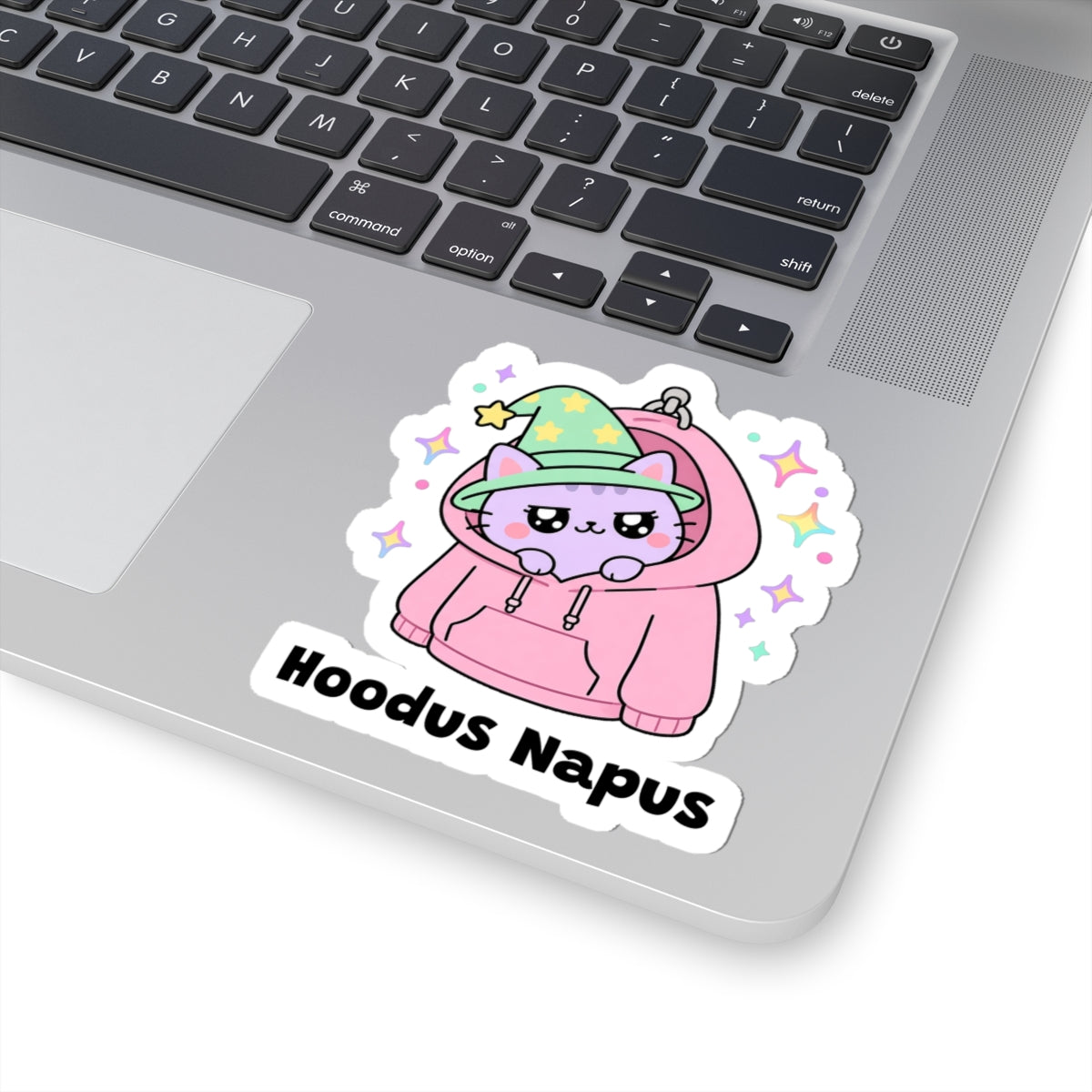 Hoodus Napus wizard cat sticker stuck on a silver laptop next to the keyboard