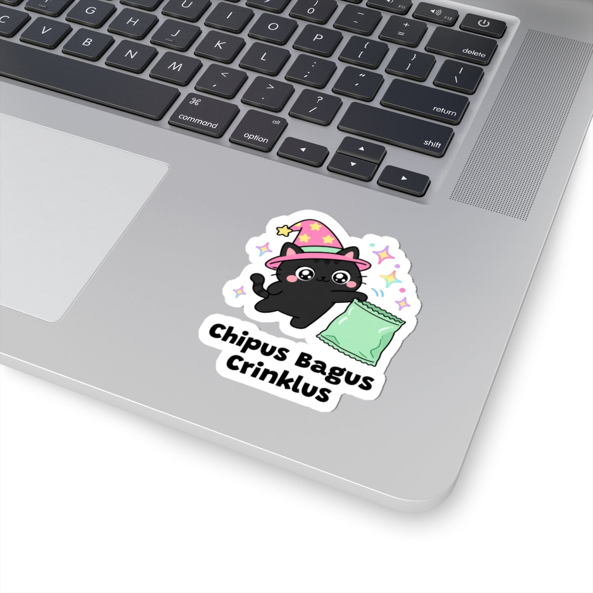 Chipus Bagus Crinklus wizard cat sticker stuck on a silver laptop next to the keyboard