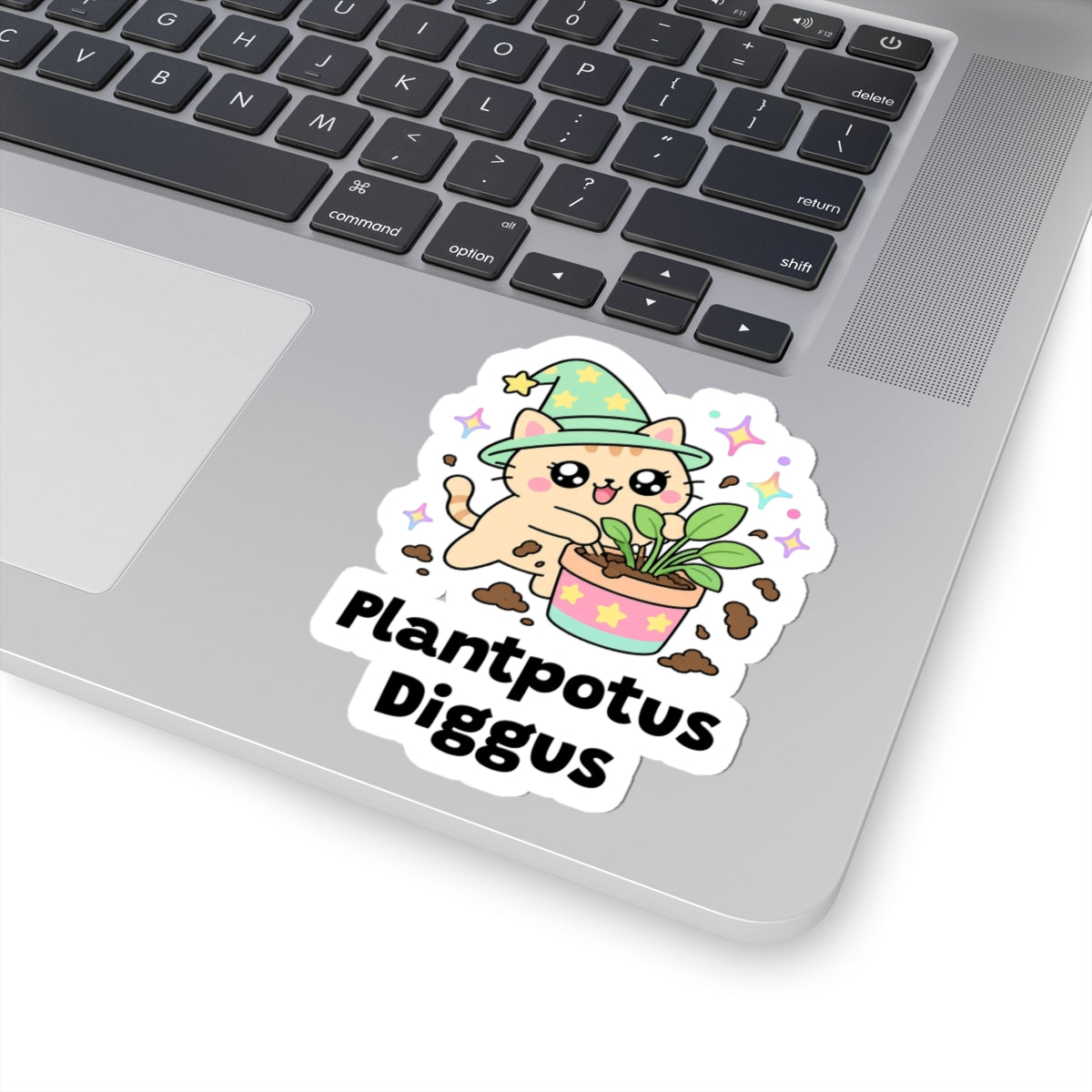 Plantpotus Diggus wizard cat sticker stuck on a silver laptop next to the keyboard