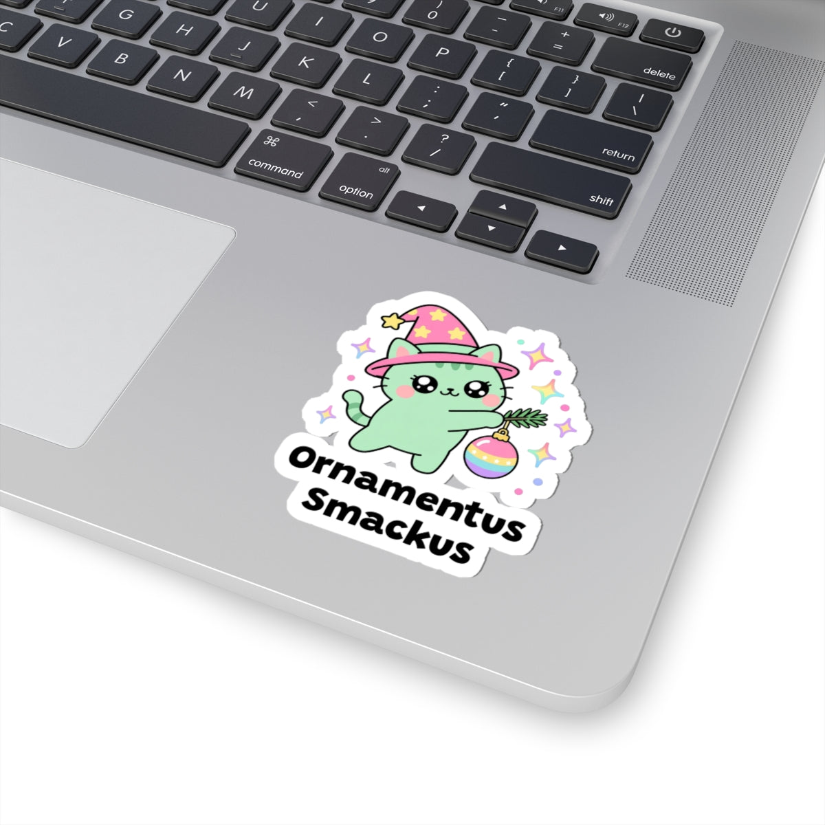 Ornamentus Smackus wizard cat sticker stuck on a silver laptop next to the keyboard