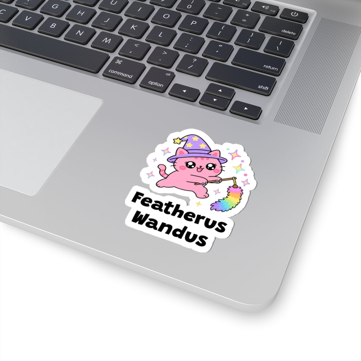 Featherus Wandus wizard cat sticker stuck on a silver laptop next to the keyboard