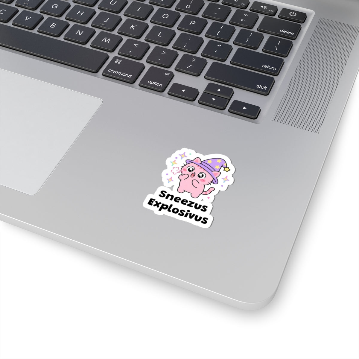 Sneezus Explosivus wizard cat sticker stuck on a silver laptop next to the keyboard