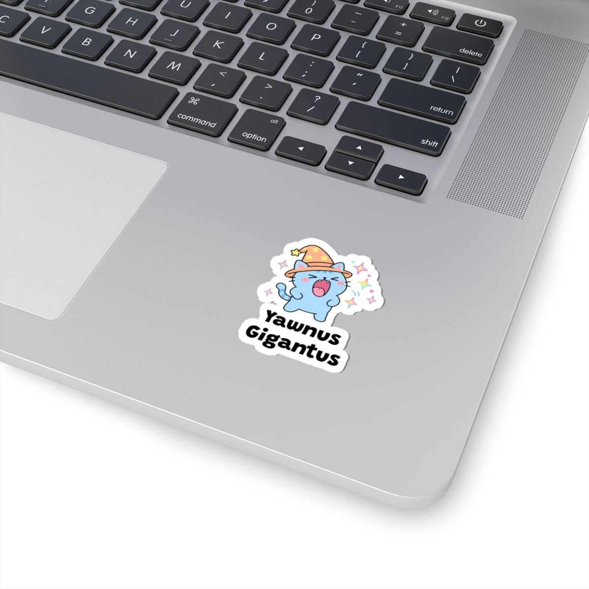 Yawnus Gigantus wizard cat sticker stuck on a silver laptop next to the keyboard