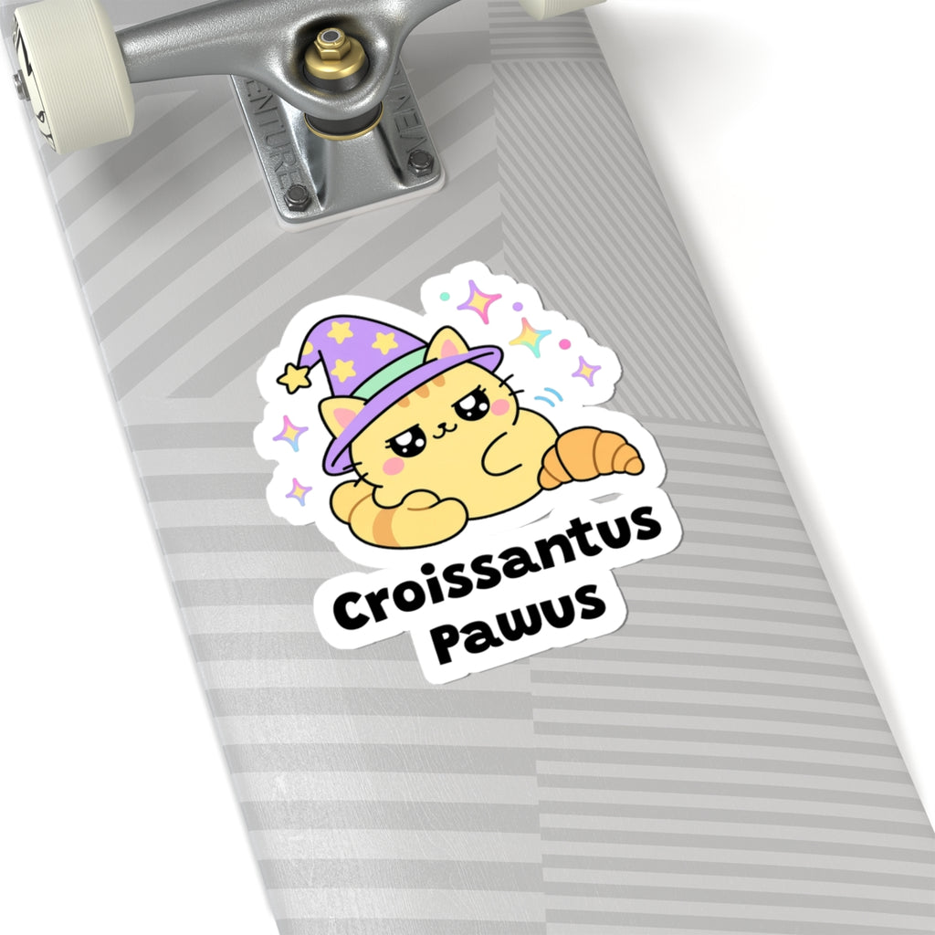 Croissantus Pawus wizard cat sticker on a grey skateboard deck near the truck