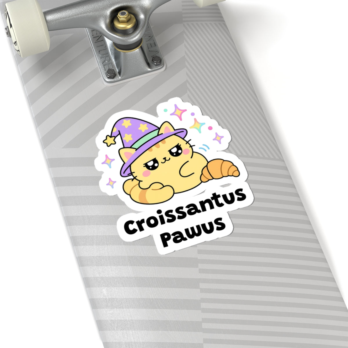 Croissantus Pawus wizard cat sticker on a grey skateboard deck near the truck