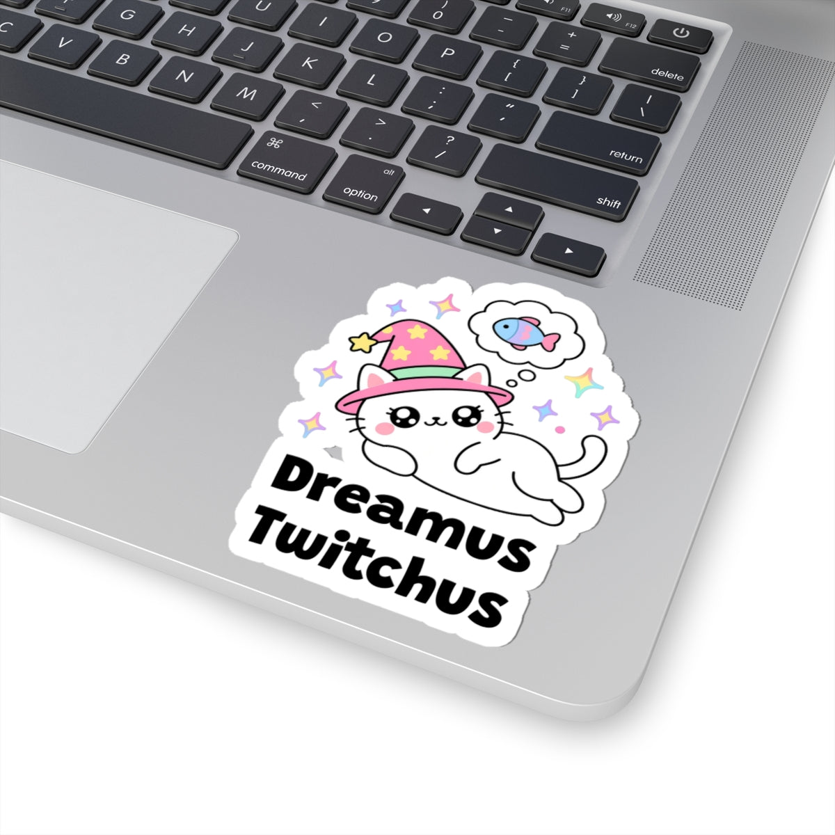 Dreamus Twitchus wizard cat sticker stuck on a silver laptop next to the keyboard