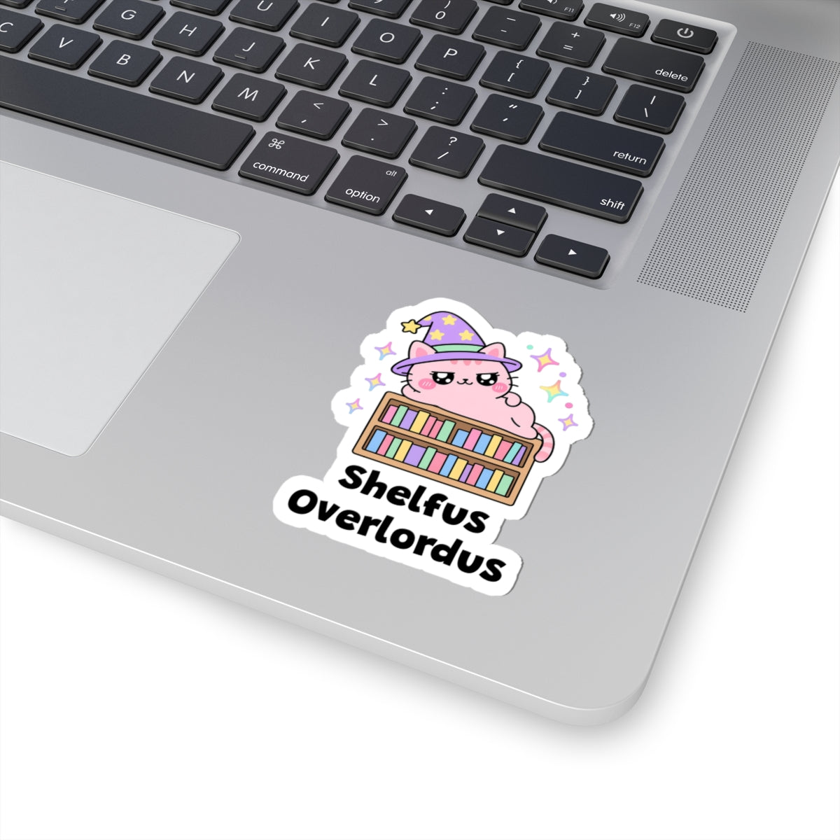 Shelfus Overlordus wizard cat sticker stuck on a silver laptop next to the keyboard