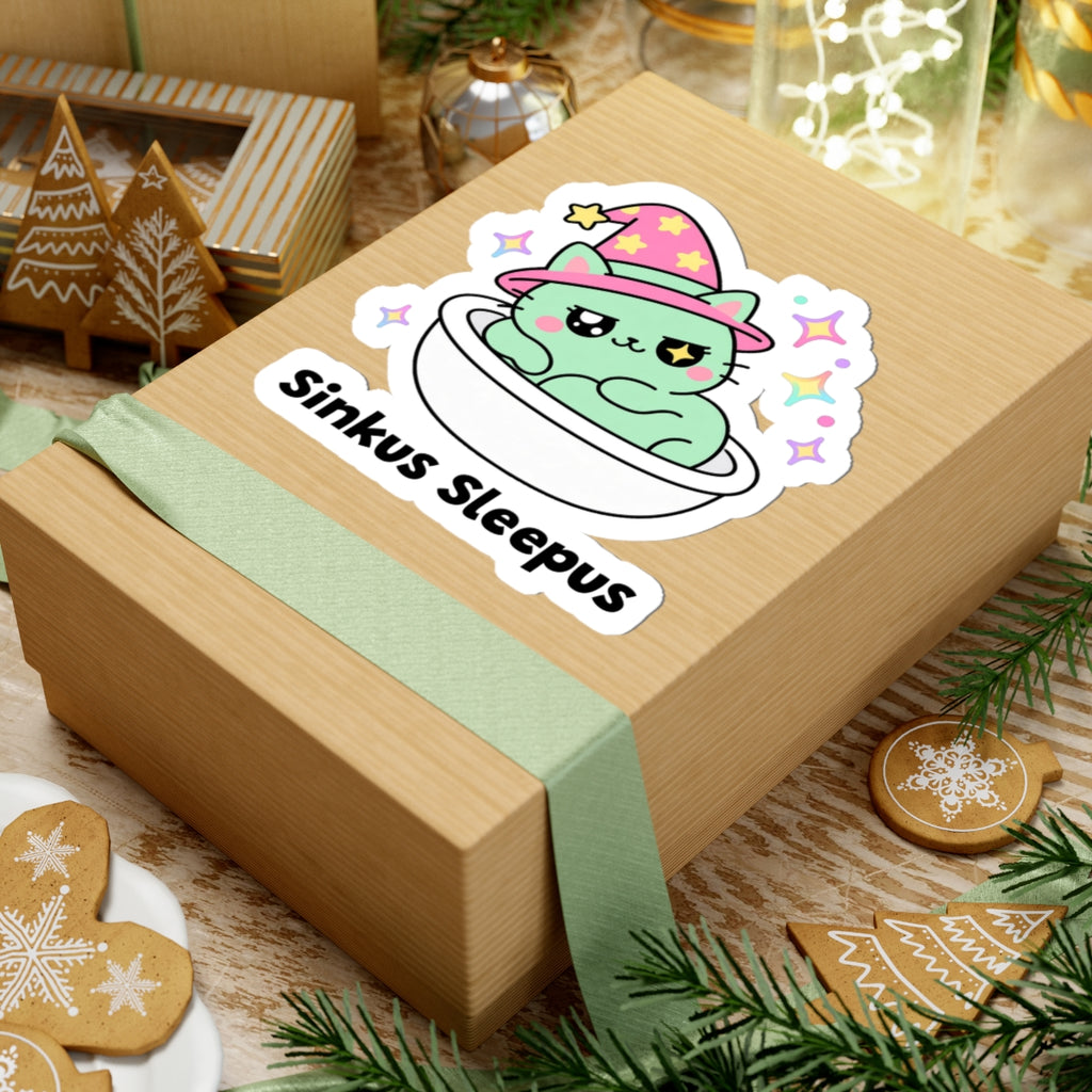 Sinkus Sleepus wizard cat sticker on a kraft gift box with a green ribbon and holiday cookies