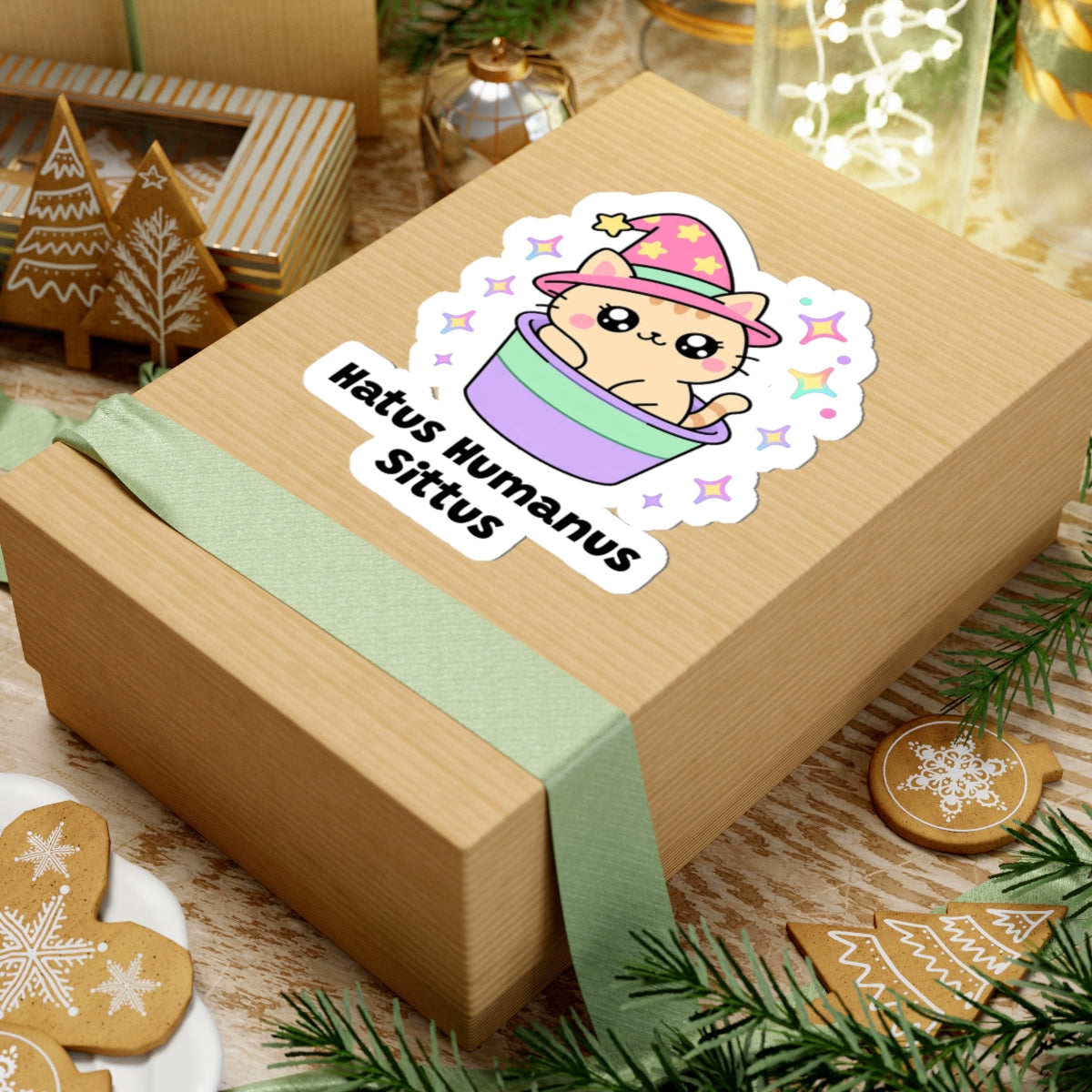 Hatus Humanus Sittus wizard cat sticker on a kraft gift box with a green ribbon and holiday cookies