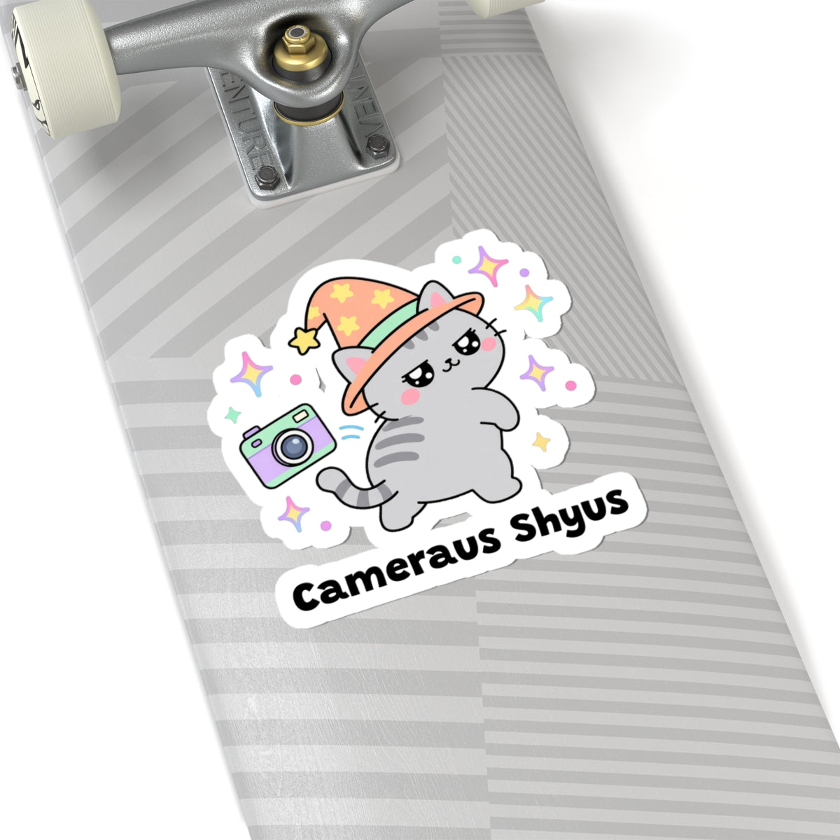 Cameraus Shyus wizard cat sticker on a grey skateboard deck near the truck