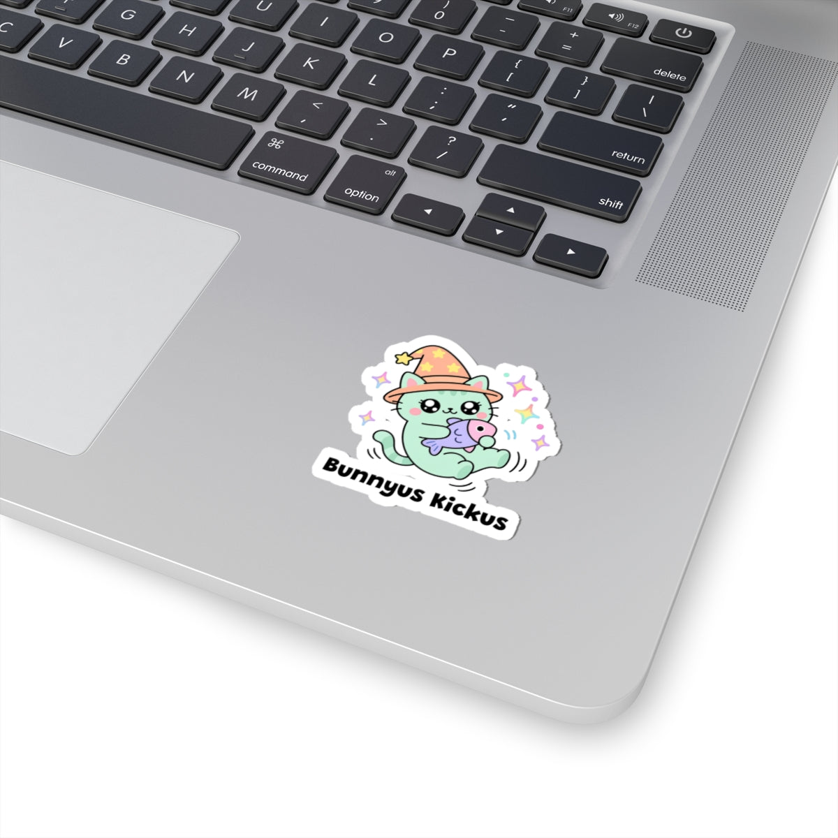 Bunnyus Kickus wizard cat sticker stuck on a silver laptop next to the keyboard