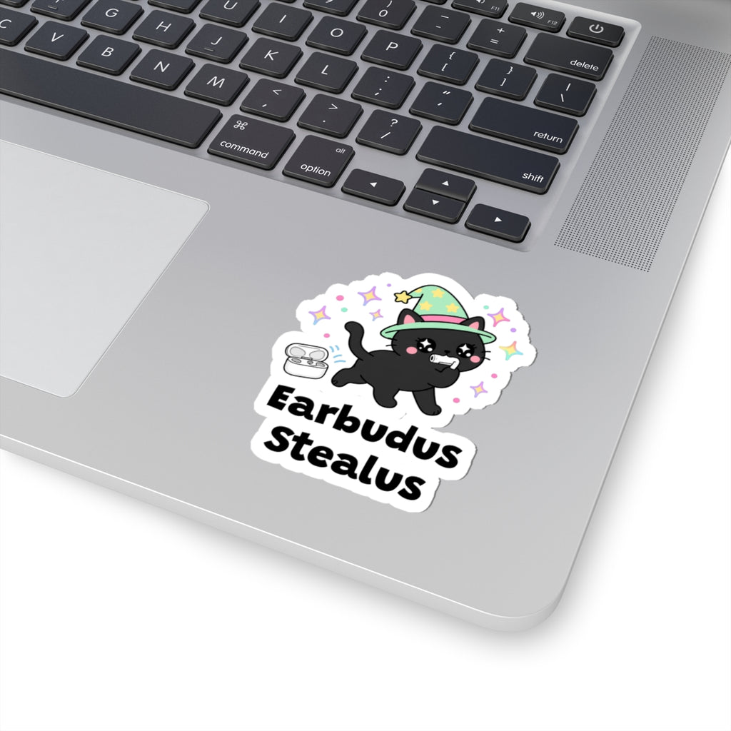 Earbudus Stealus wizard cat sticker stuck on a silver laptop next to the keyboard