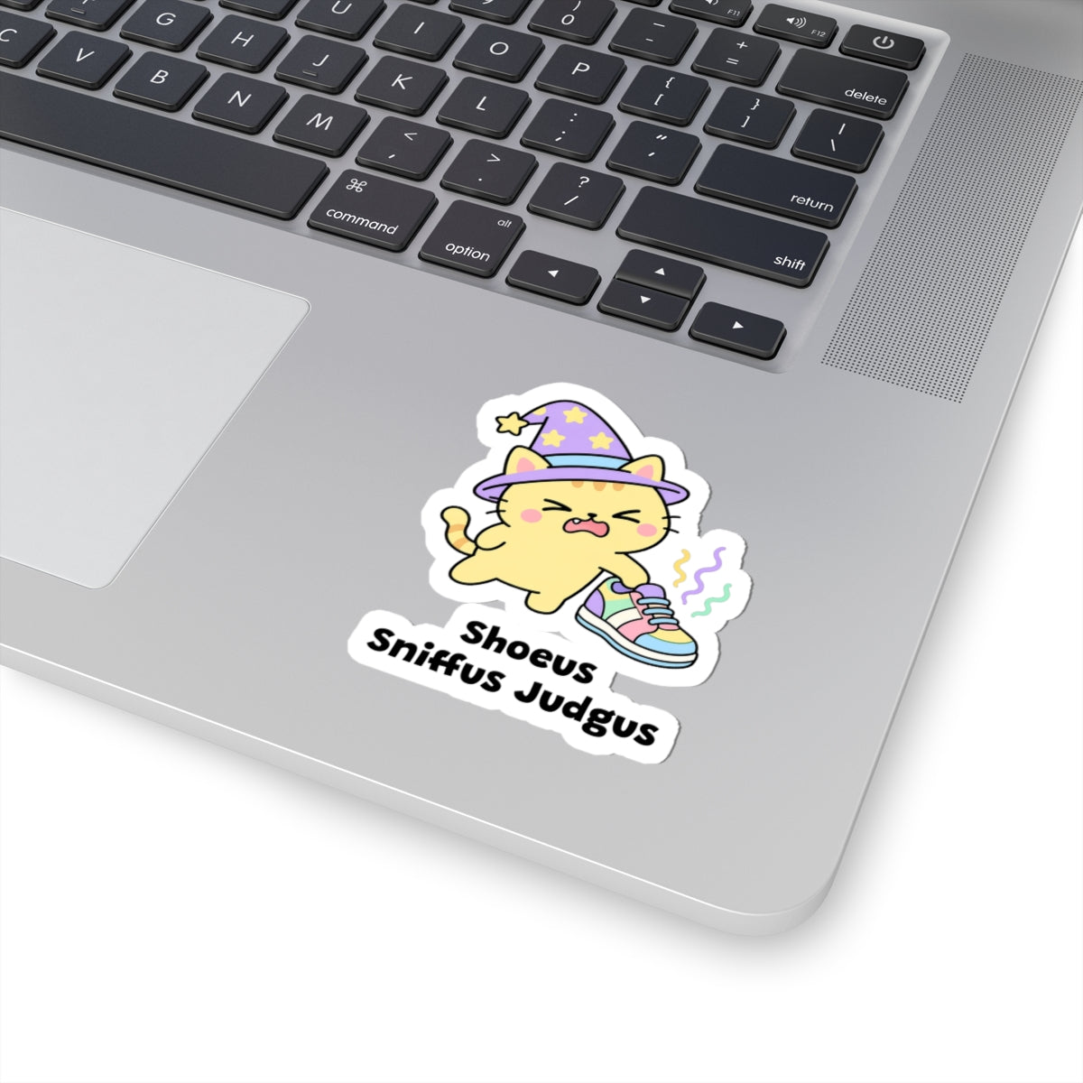 Shoeus Sniffus Judgus wizard cat sticker stuck on a silver laptop next to the keyboard