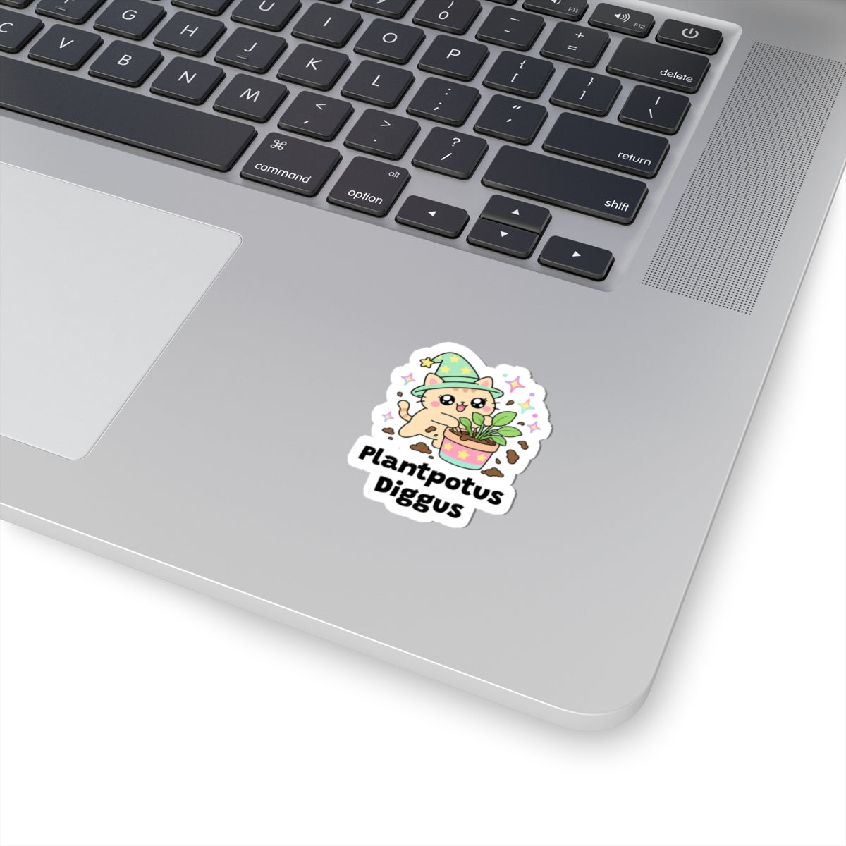 Plantpotus Diggus wizard cat sticker stuck on a silver laptop next to the keyboard