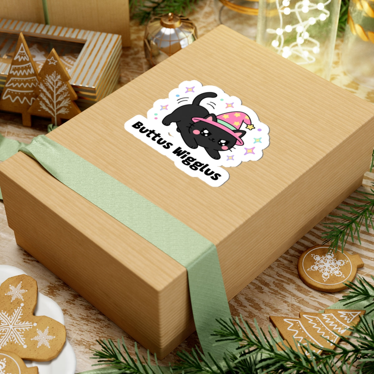 Buttus Wigglus wizard cat sticker on a kraft gift box with a green ribbon and holiday cookies