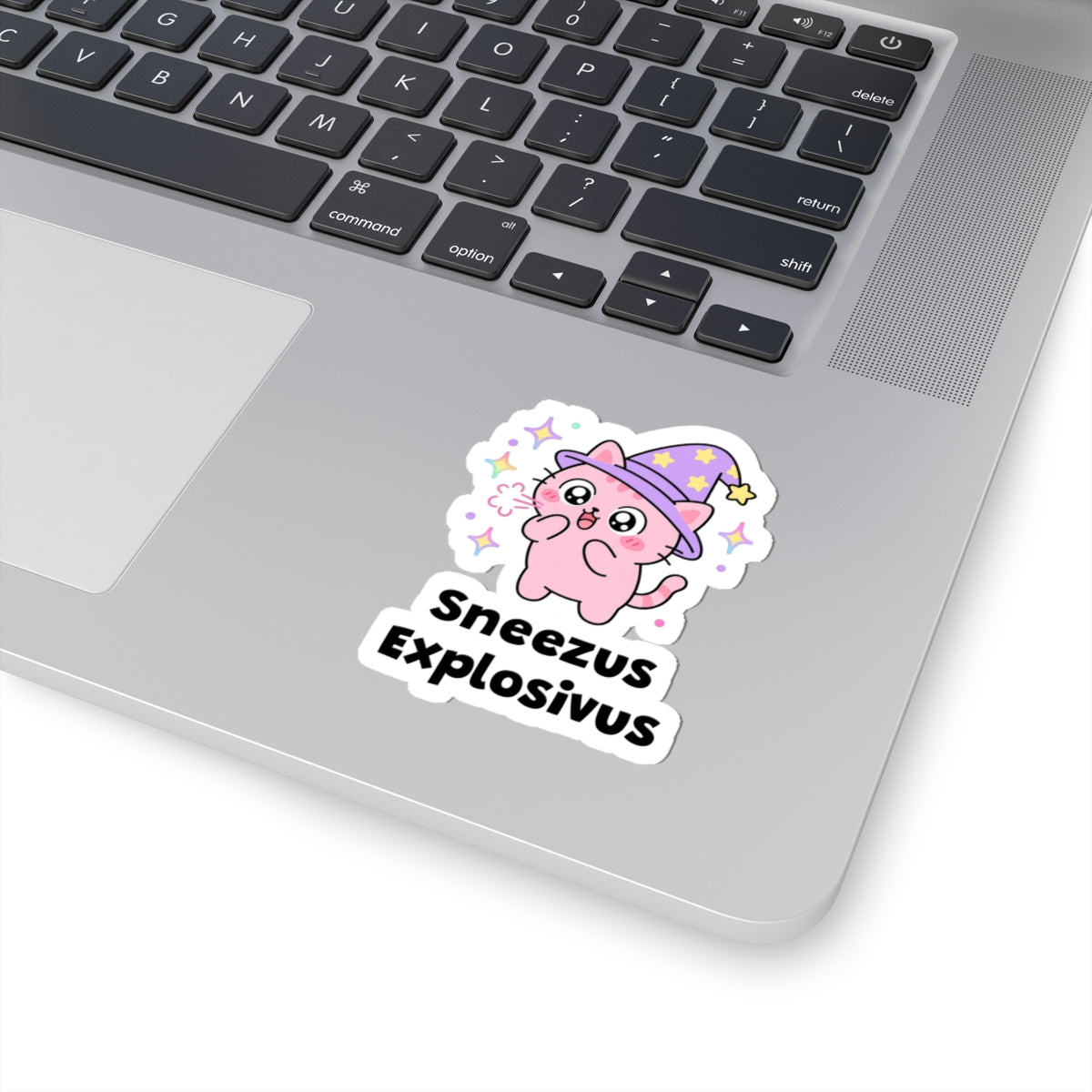 Sneezus Explosivus wizard cat sticker stuck on a silver laptop next to the keyboard