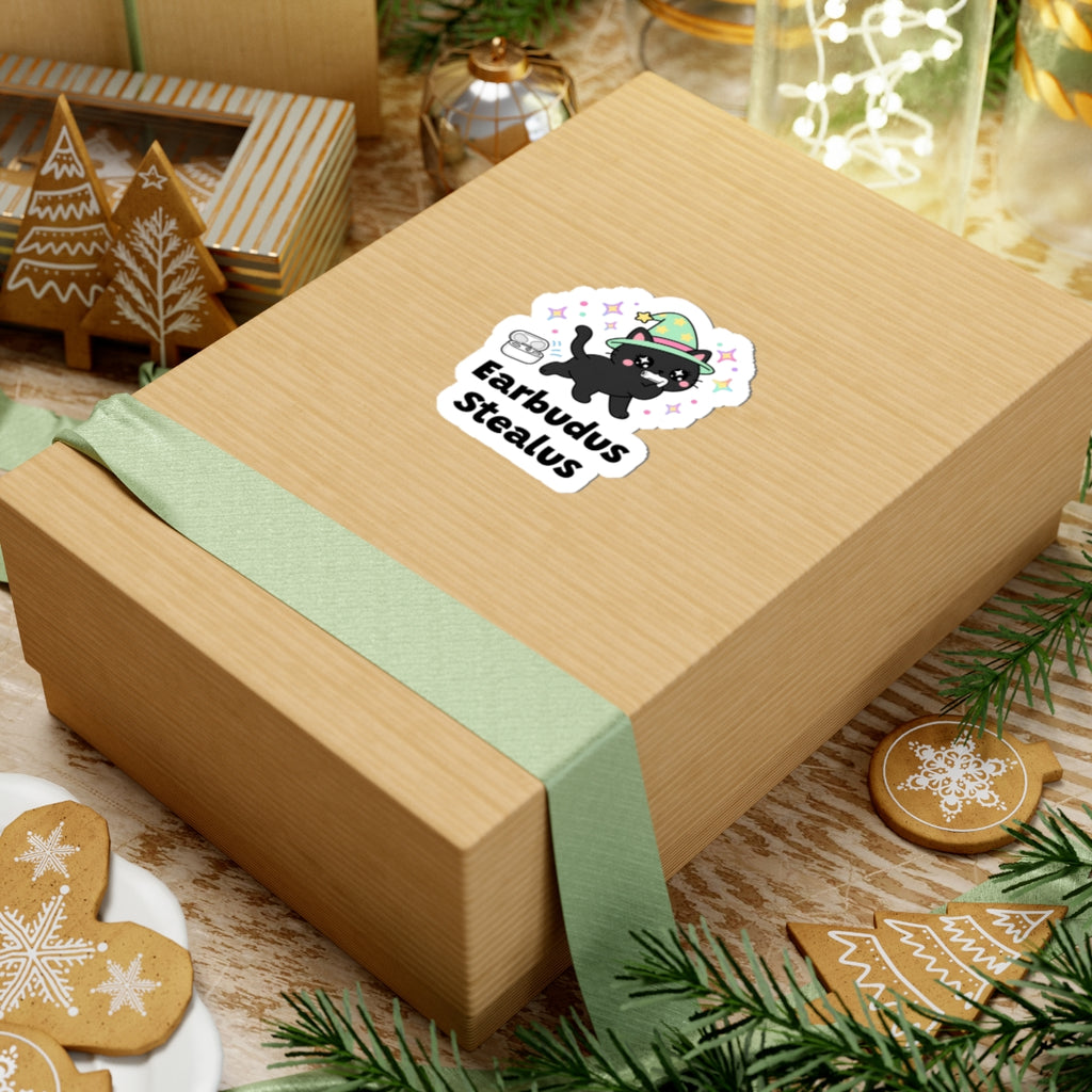 Earbudus Stealus wizard cat sticker on a kraft gift box with a green ribbon and holiday cookies