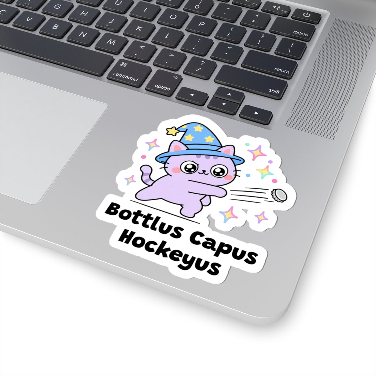 Bottlus Capus Hockeyus wizard cat sticker stuck on a silver laptop next to the keyboard
