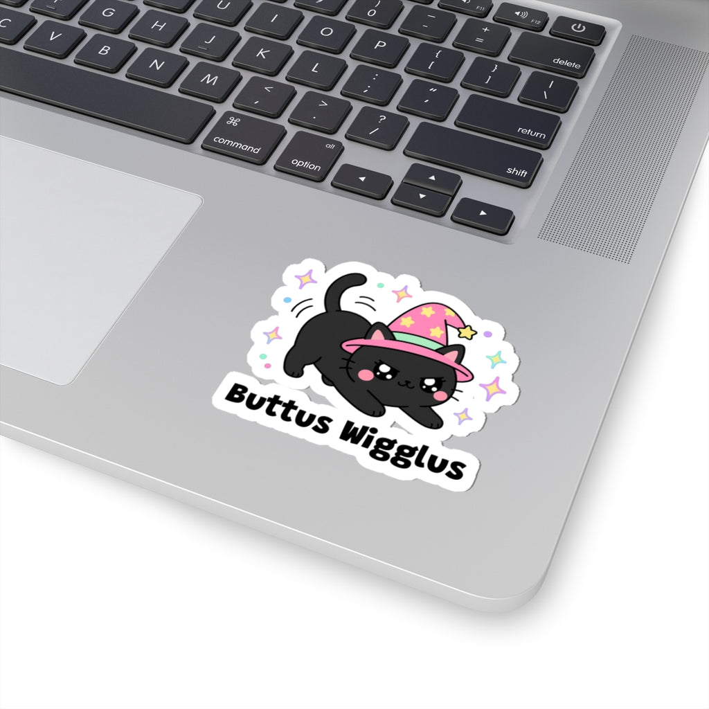 Buttus Wigglus wizard cat sticker stuck on a silver laptop next to the keyboard