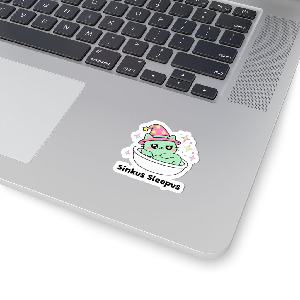Sinkus Sleepus wizard cat sticker stuck on a silver laptop next to the keyboard