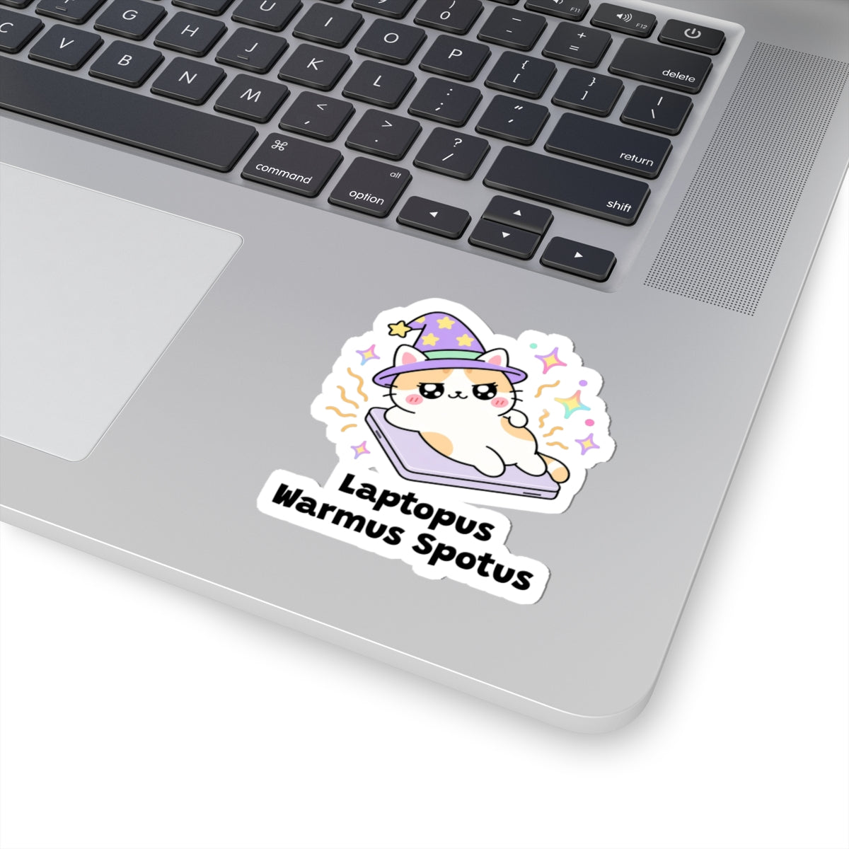 Laptopus Warmus Spotus wizard cat sticker stuck on a silver laptop next to the keyboard