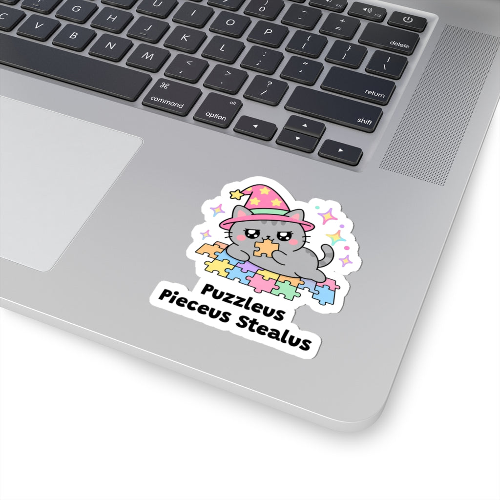 Puzzleus Pieceus Stealus wizard cat sticker stuck on a silver laptop next to the keyboard