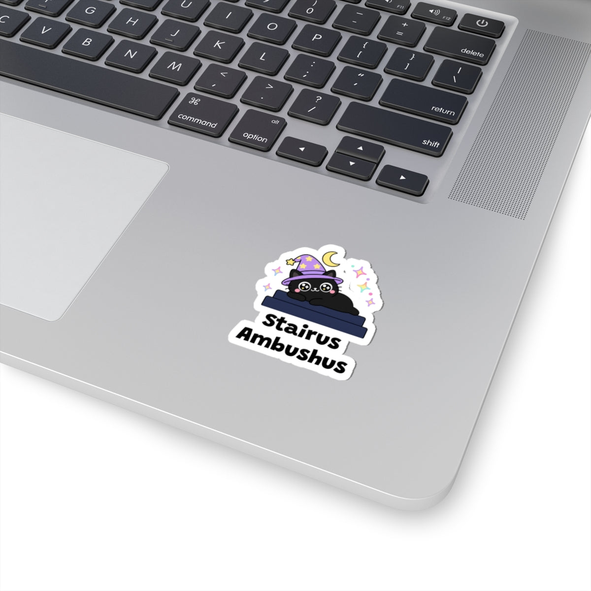 Stairus Ambushus wizard cat sticker stuck on a silver laptop next to the keyboard