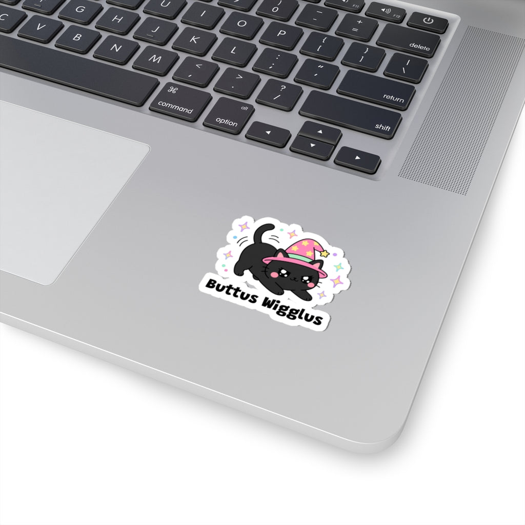 Buttus Wigglus wizard cat sticker stuck on a silver laptop next to the keyboard