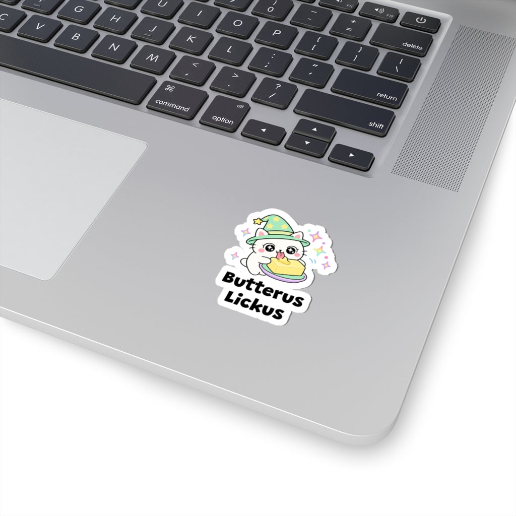 Butterus Lickus wizard cat sticker stuck on a silver laptop next to the keyboard