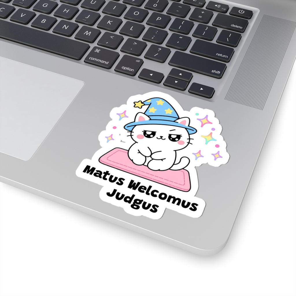 Matus Welcomus Judgus wizard cat sticker stuck on a silver laptop next to the keyboard