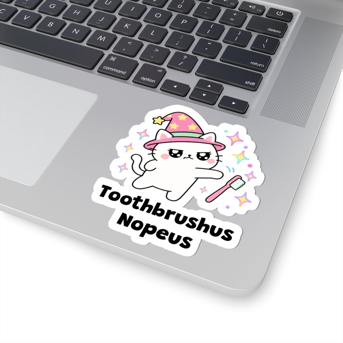 Toothbrushus Nopeus wizard cat sticker stuck on a silver laptop next to the keyboard