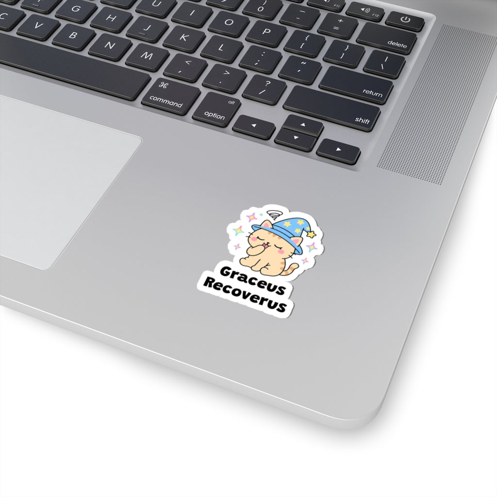 Graceus Recoverus wizard cat sticker stuck on a silver laptop next to the keyboard