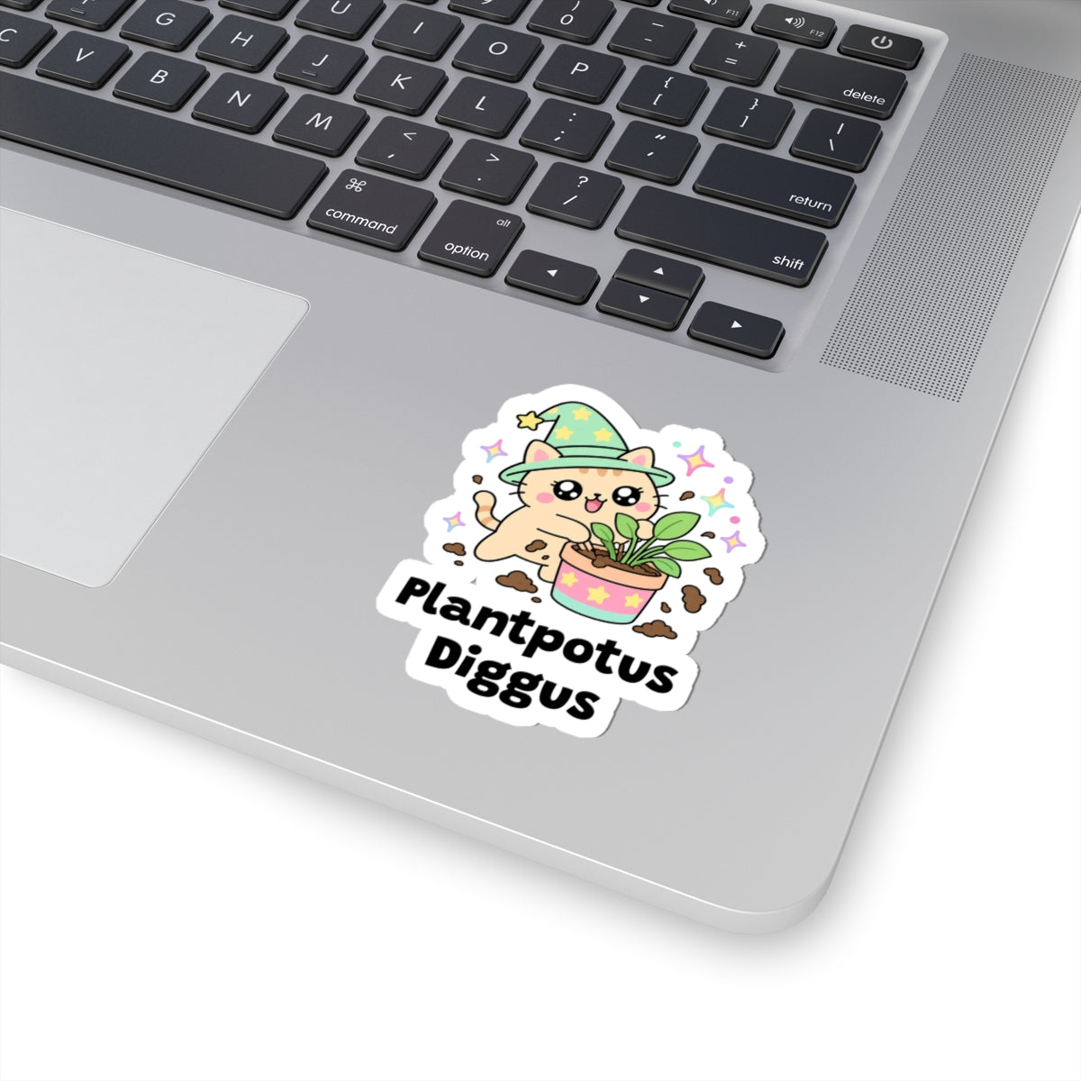 Plantpotus Diggus wizard cat sticker stuck on a silver laptop next to the keyboard