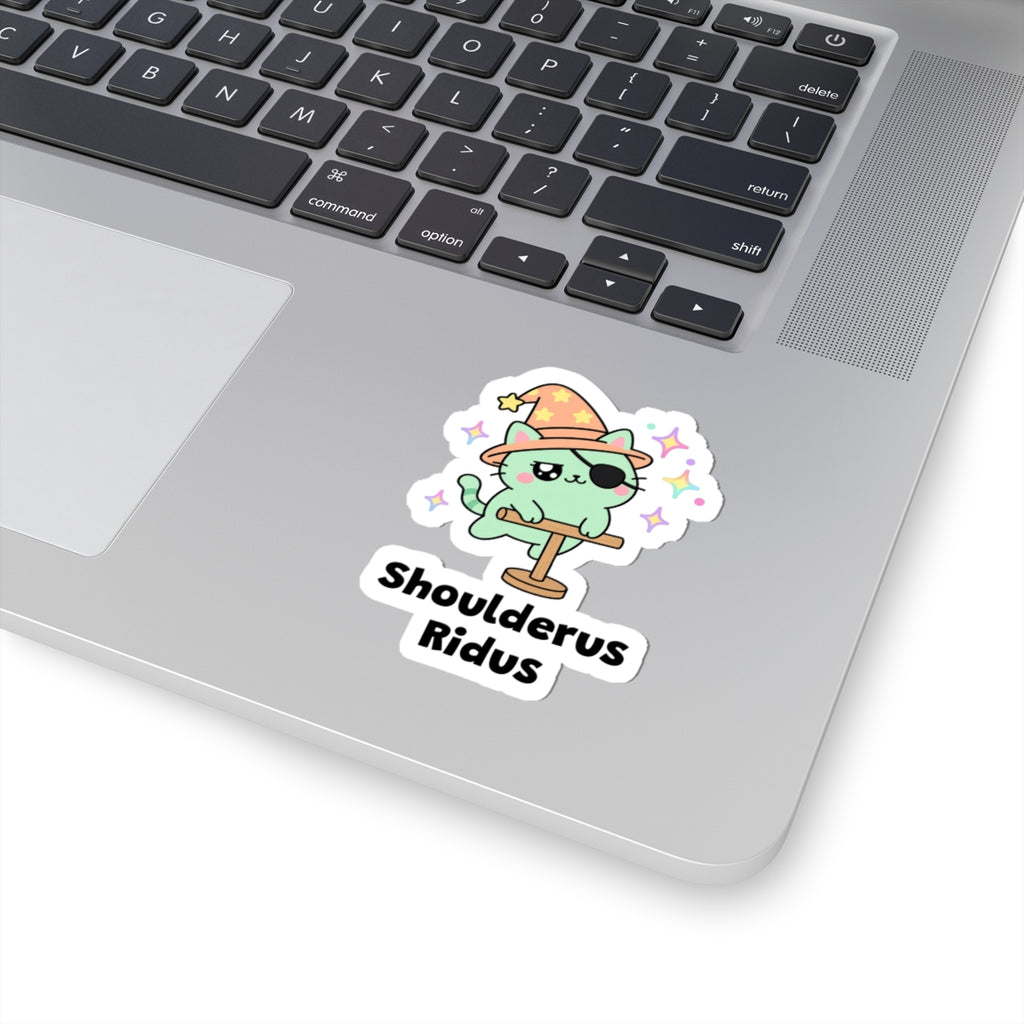 Shoulderus Ridus wizard cat sticker stuck on a silver laptop next to the keyboard