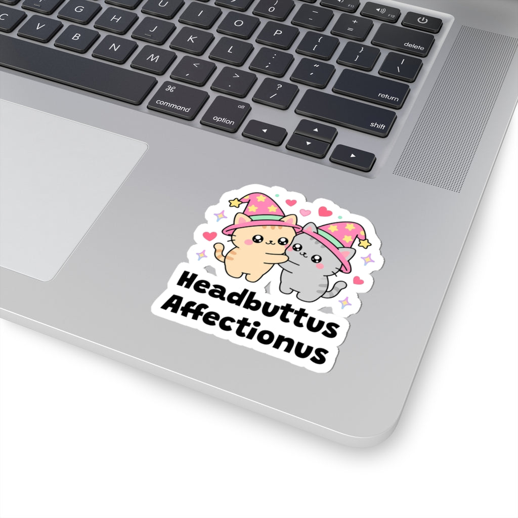 Headbuttus Affectionus wizard cat sticker stuck on a silver laptop next to the keyboard