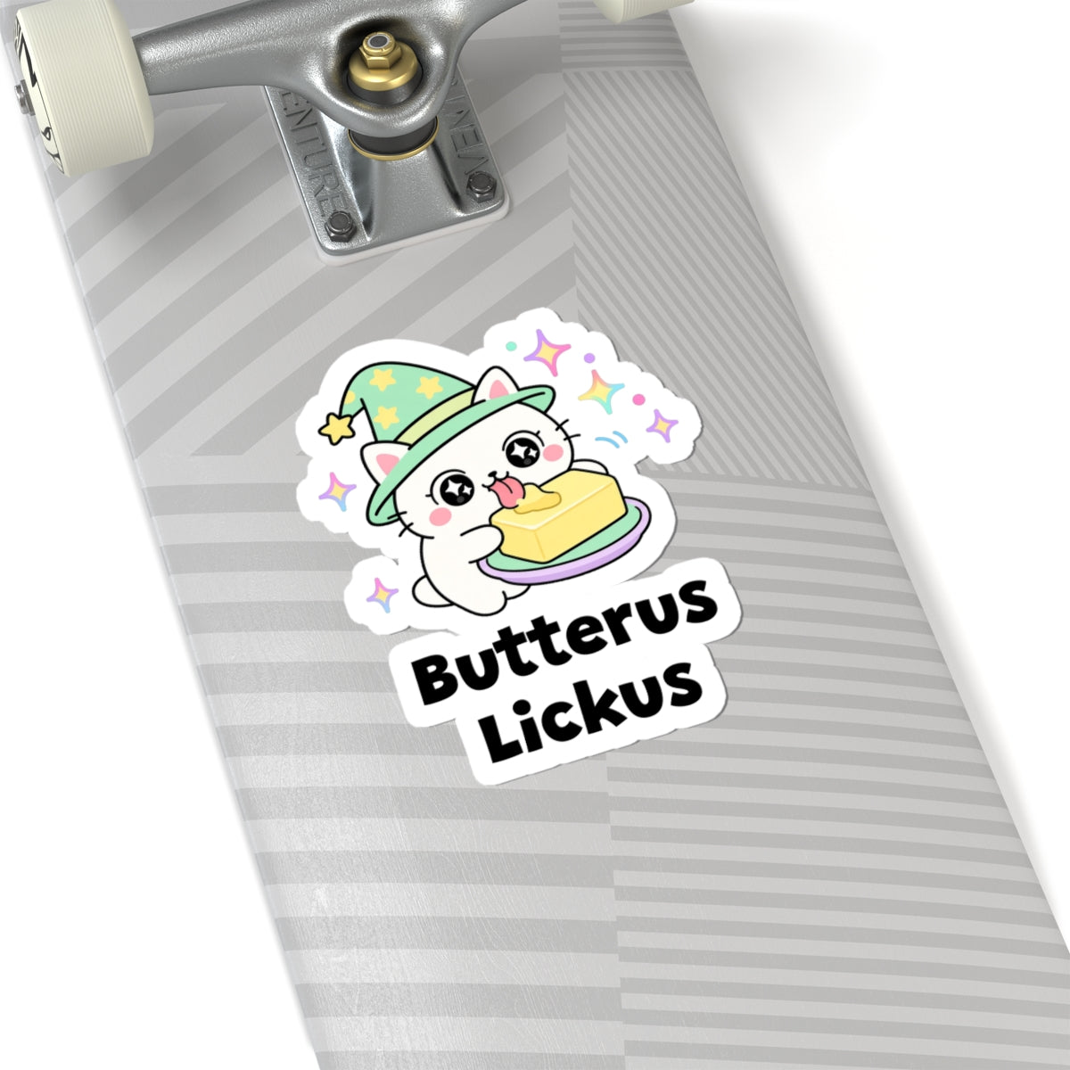 Butterus Lickus wizard cat sticker on a grey skateboard deck near the truck