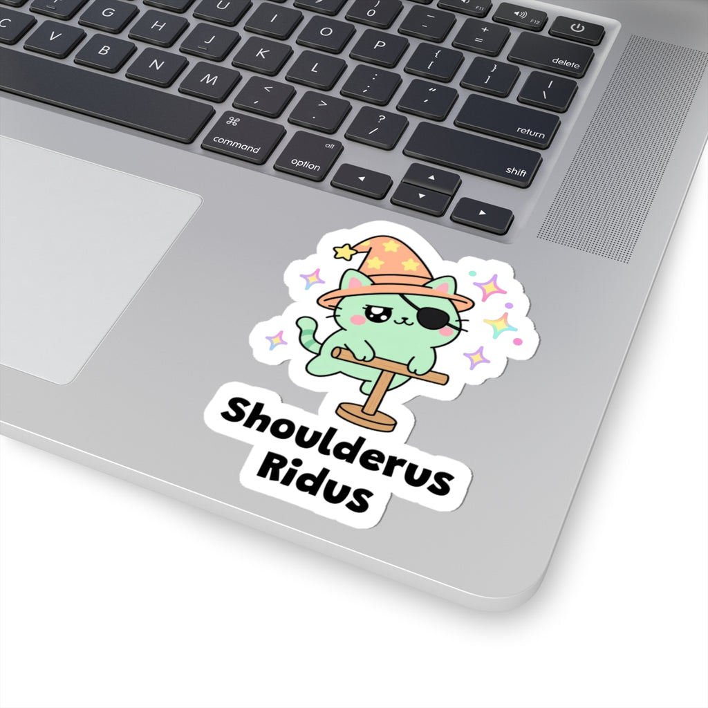 Shoulderus Ridus wizard cat sticker stuck on a silver laptop next to the keyboard