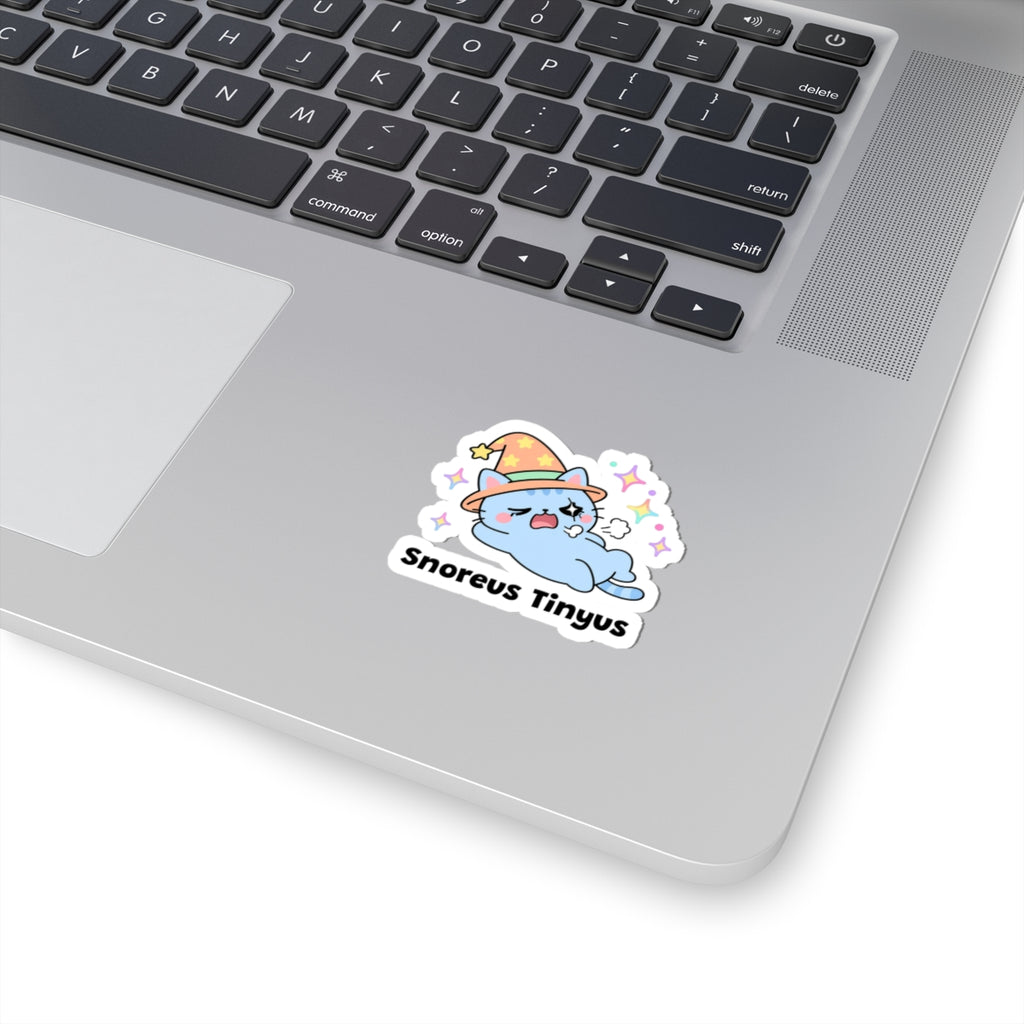 Snoreus Tinyus wizard cat sticker stuck on a silver laptop next to the keyboard