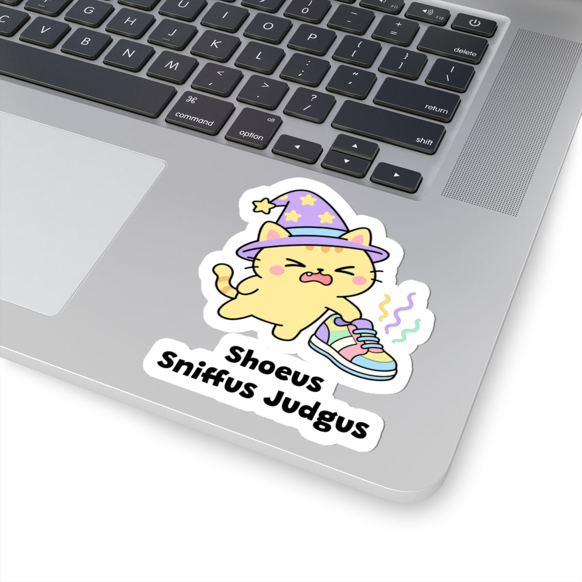 Shoeus Sniffus Judgus wizard cat sticker stuck on a silver laptop next to the keyboard