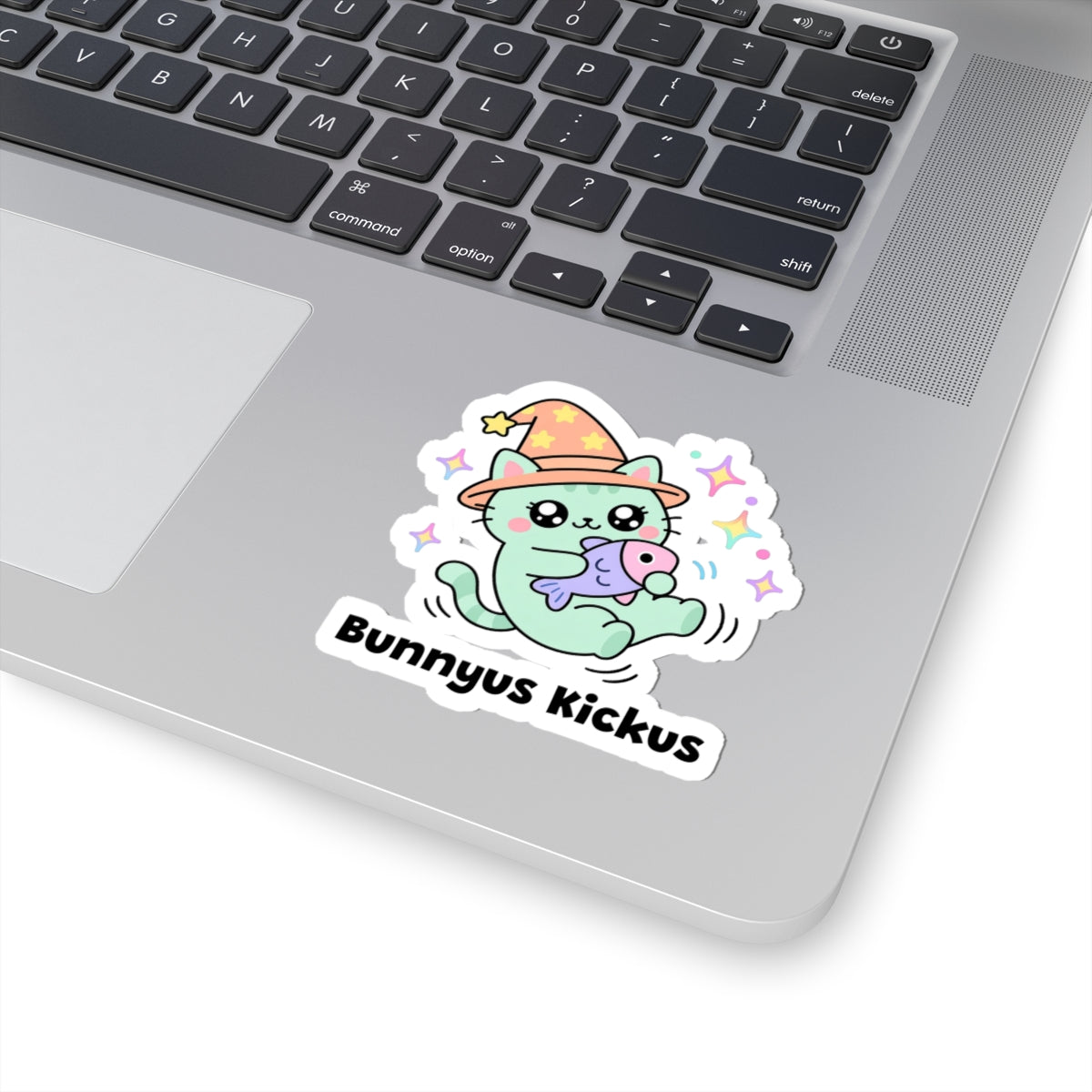 Bunnyus Kickus wizard cat sticker stuck on a silver laptop next to the keyboard