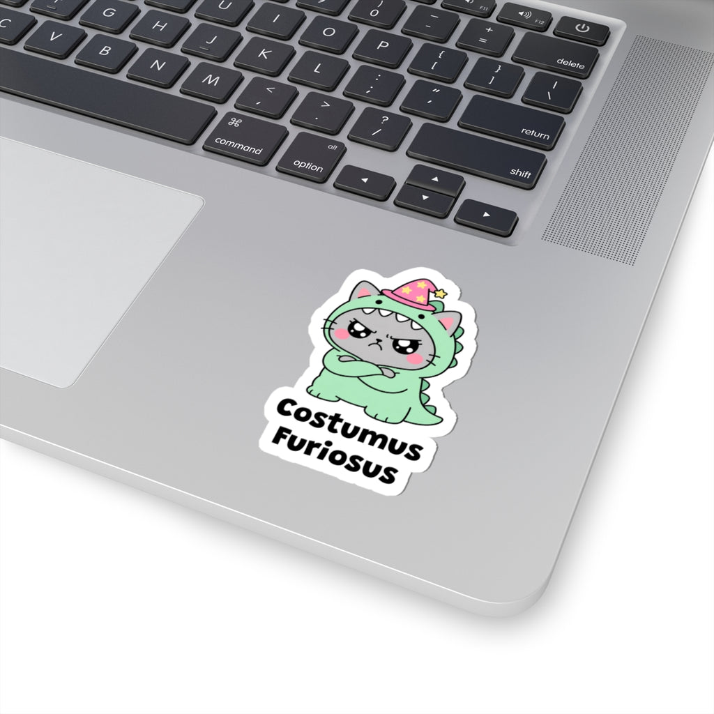 Costumus Furiosus wizard cat sticker stuck on a silver laptop next to the keyboard