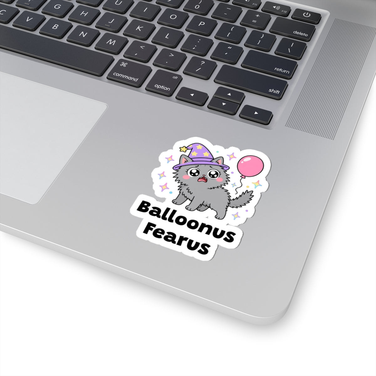 Balloonus Fearus wizard cat sticker stuck on a silver laptop next to the keyboard