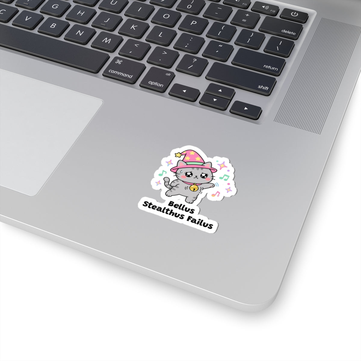 Bellus Stealthus Failus wizard cat sticker stuck on a silver laptop next to the keyboard
