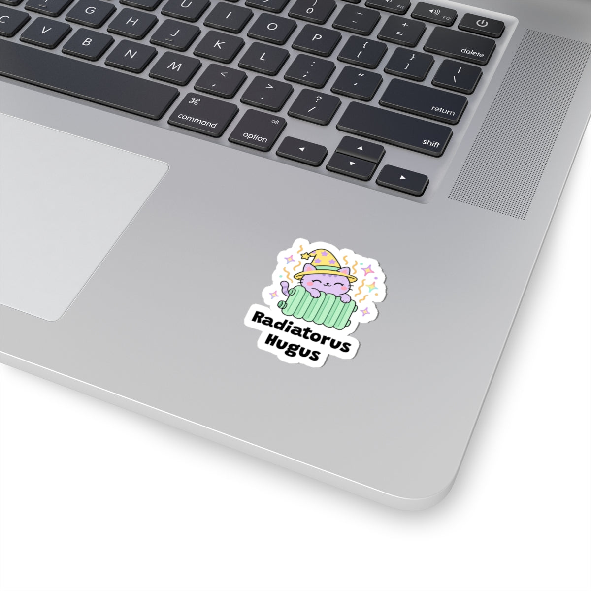 Radiatorus Hugus wizard cat sticker stuck on a silver laptop next to the keyboard
