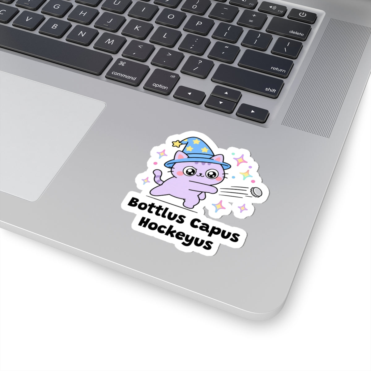 Bottlus Capus Hockeyus wizard cat sticker stuck on a silver laptop next to the keyboard