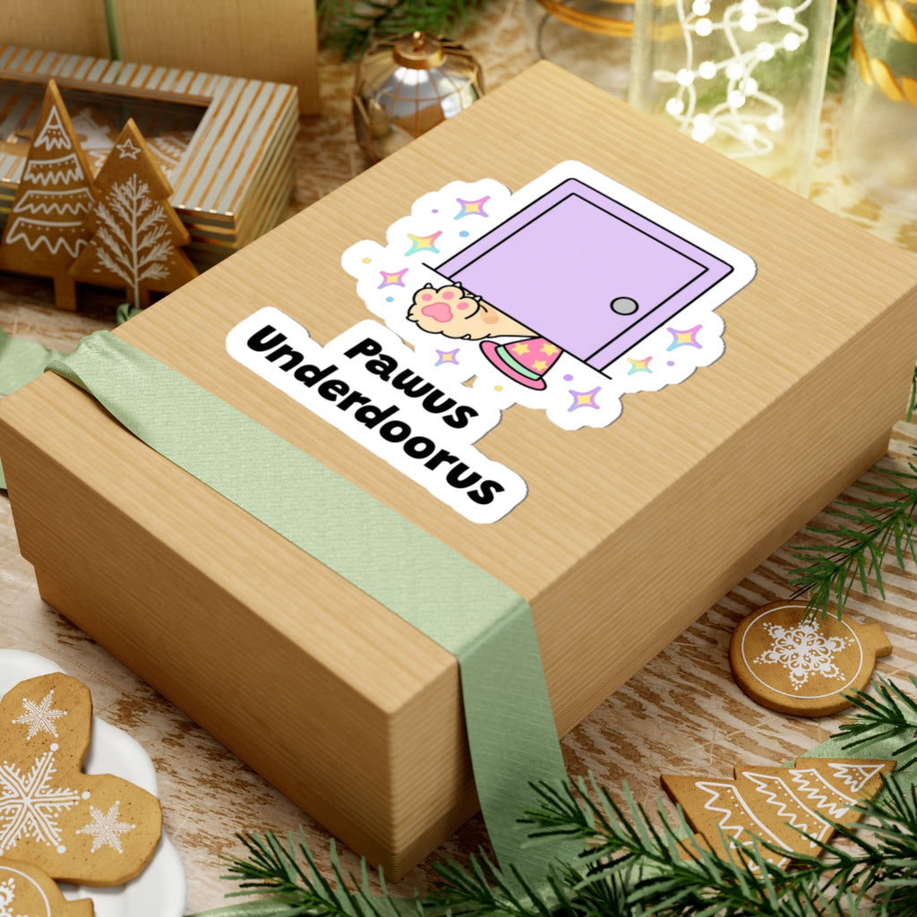 Pawus Underdoorus wizard cat sticker on a kraft gift box with a green ribbon and holiday cookies
