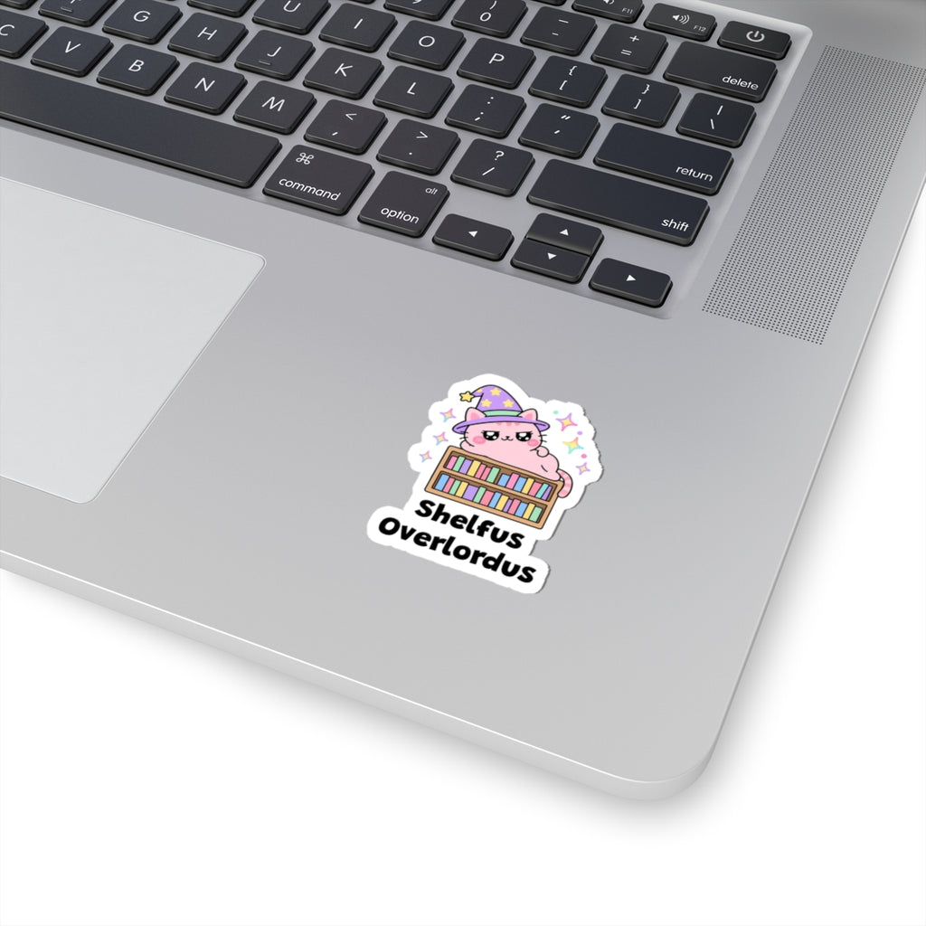 Shelfus Overlordus wizard cat sticker stuck on a silver laptop next to the keyboard